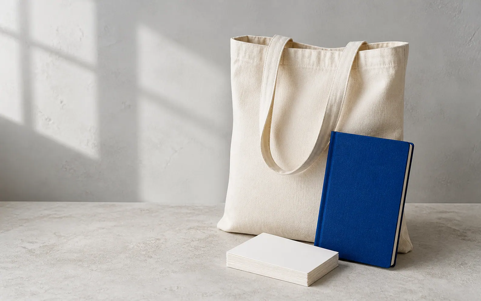 Blank natural canvas tote bag, cobalt notebook and blank postcards ready for customization