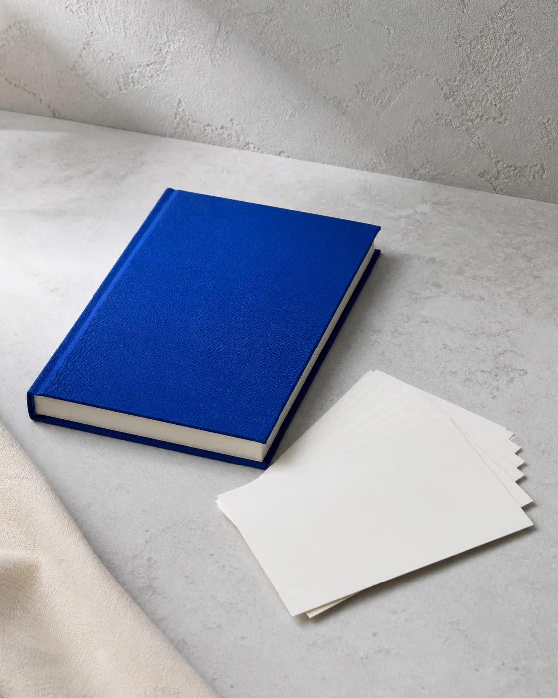 Blank cobalt clothbound notebook and unprinted postcards ready for customization